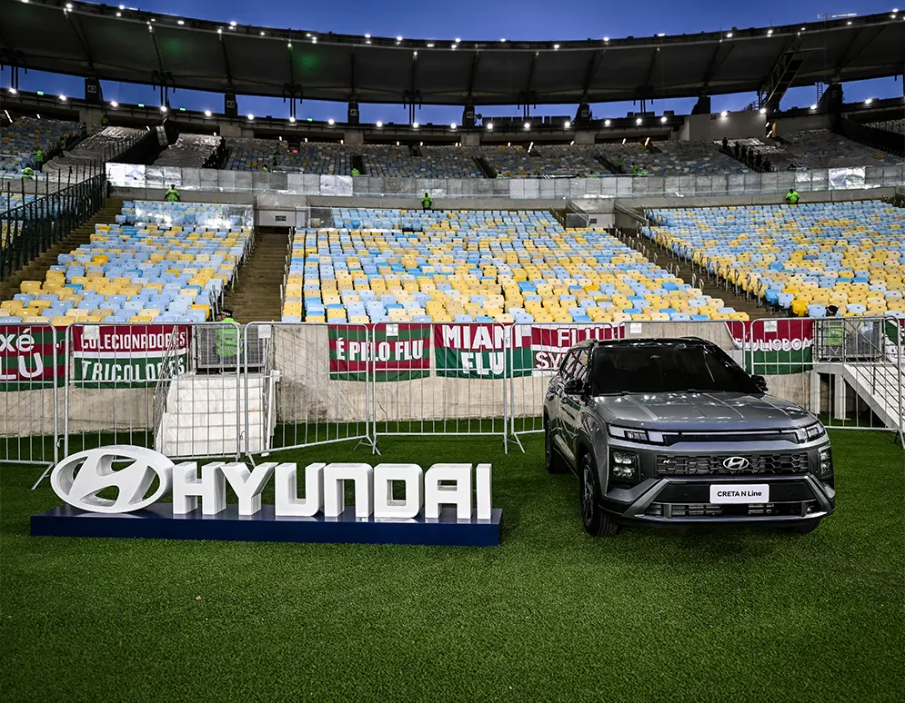 CRETA N Line cinza ao lado de placa da Hyundai dentro de um estádio de futebol.
