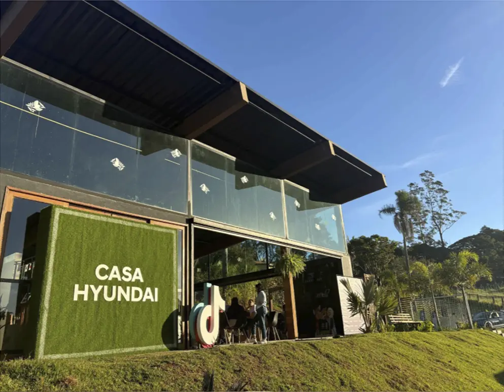Fachada da Casa Hyundai durante o dia com influenciadores conversando. 