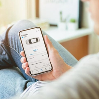 Pessoa sentada com o celular na mão olhando para o aplicativo do Hyundai Bluelink