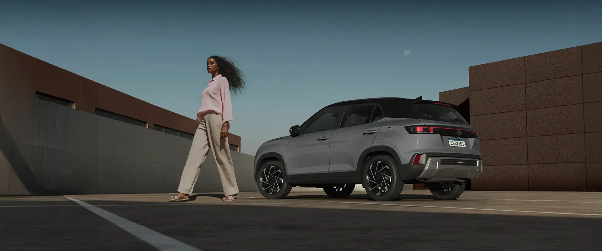 Hyundai Creta 2025 cinza estacionado em cenário urbano ao lado de uma mulher, destacando os prêmios nacionais de melhor SUV.