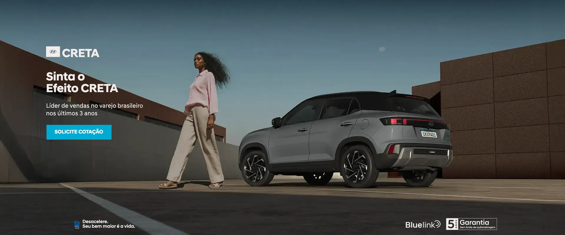 Hyundai Creta 2025 cinza estacionado em cenário urbano ao lado de uma mulher, destacando os prêmios nacionais de melhor SUV.