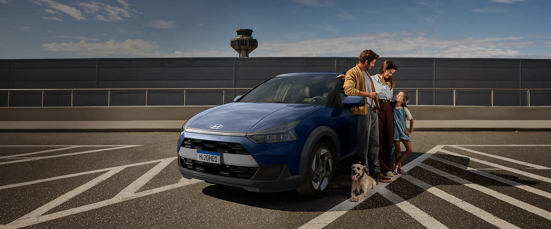 Casal, criança e cachorro ao lado do Novo Hyundai i20, retratando a evolução para um novo momento da vida em família.