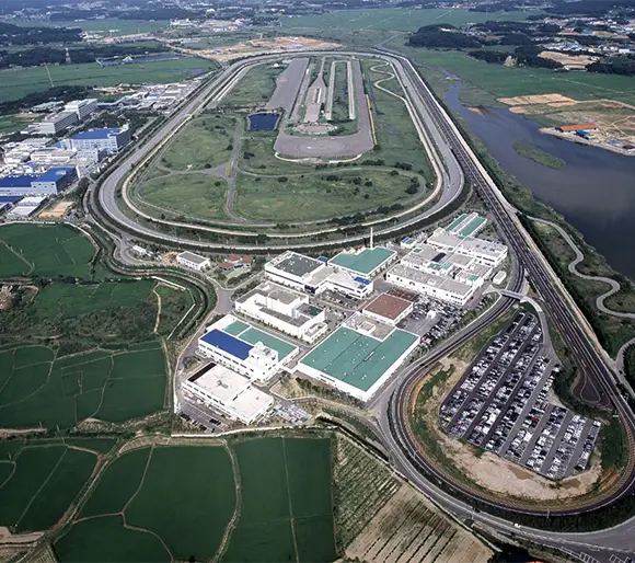 Centro de Pesquisas e Testes da Hyundai com pista de corrida e fábricas durante o dia.