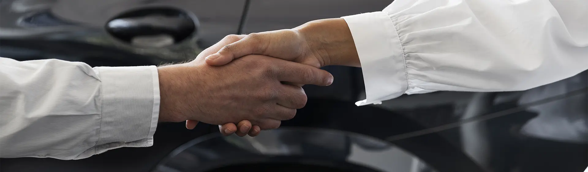 Duas pessoas apertando as mãos para concluir um negócio na Black Friday  em uma concessionária.