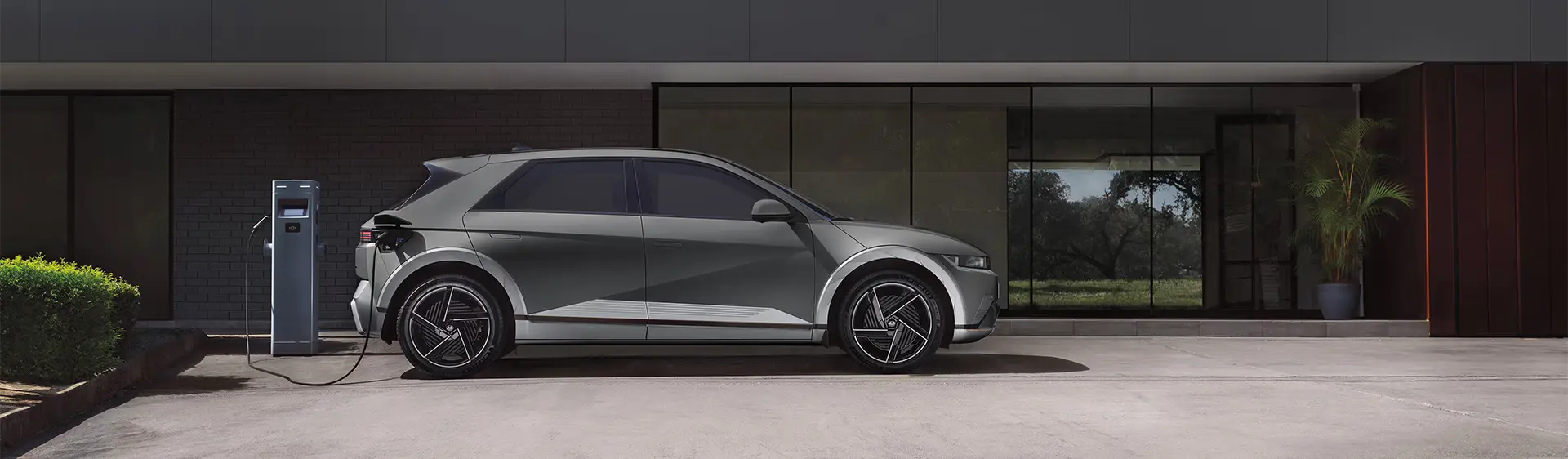 Modelo IONIQ 5 na cor cinza sendo recarregado durante o dia.