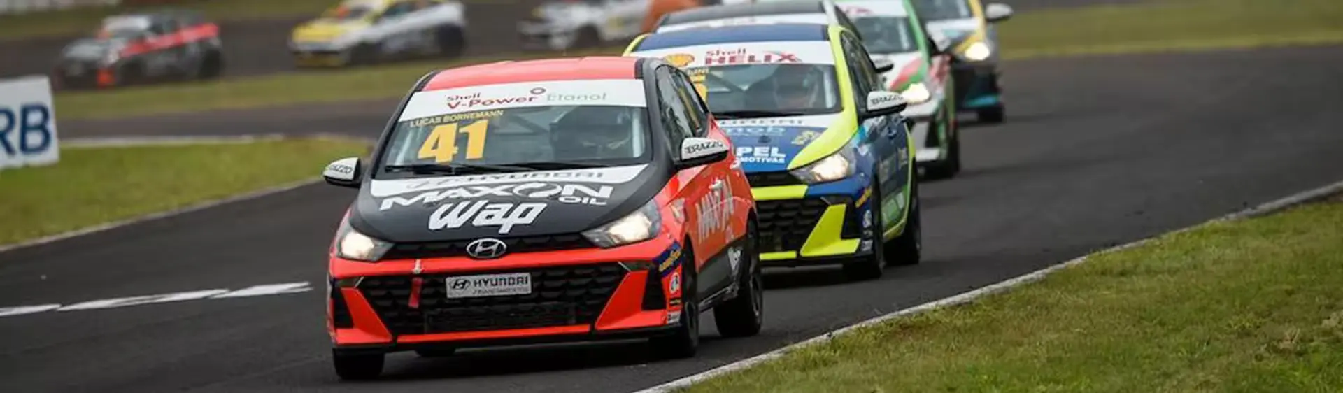 Modelos de corrida do HB20 em alta velocidade na pista durante o dia.