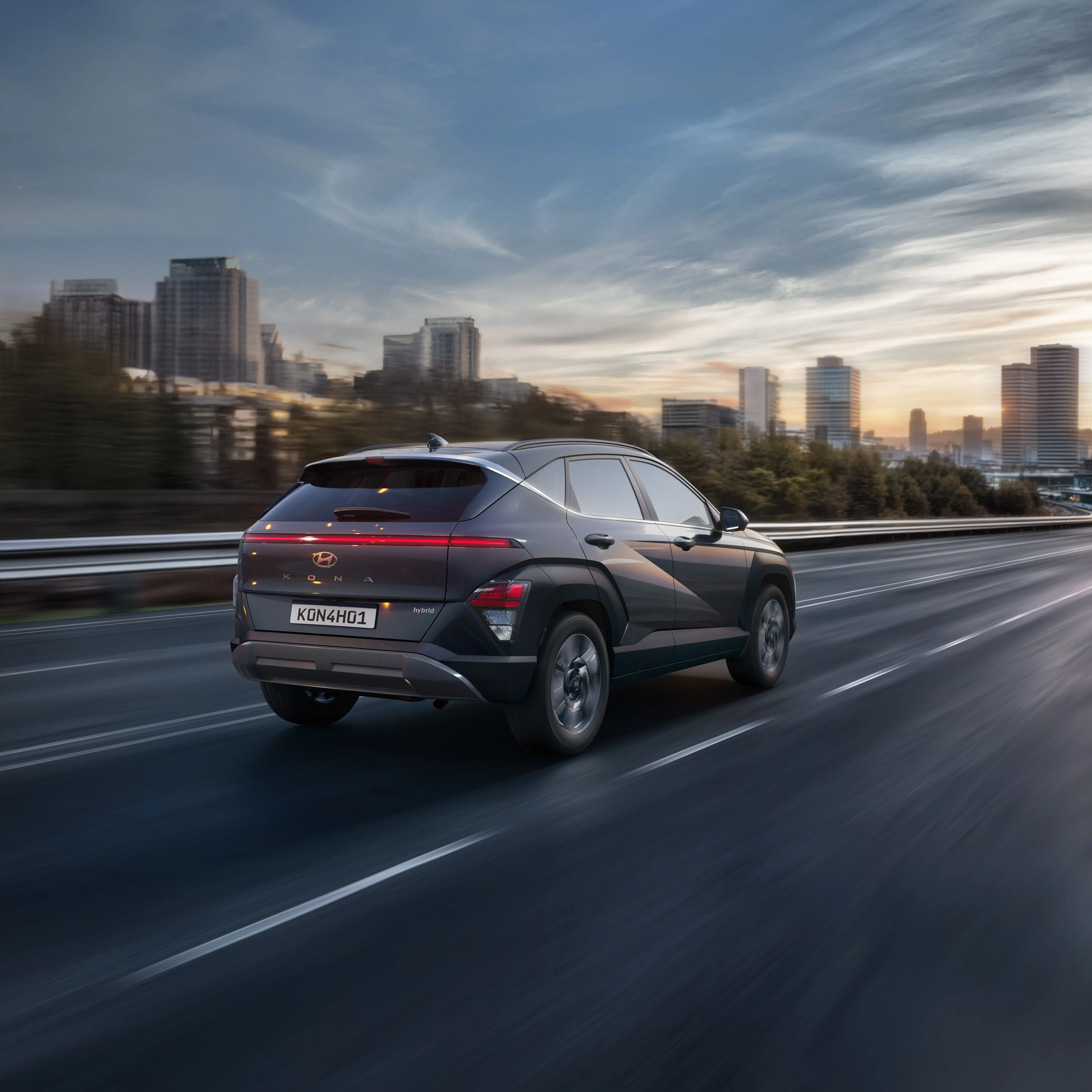 KONA Híbrido dirigindo em uma estrada com paisagem urbana ao fundo.