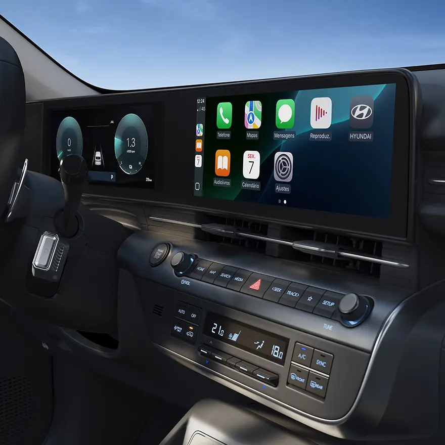 Painel frontal do KONA Híbrido, destacando o display integrado com duas telas de 12,3”, controle de ar-condicionado e câmbio tipo coluna integrado ao volante.