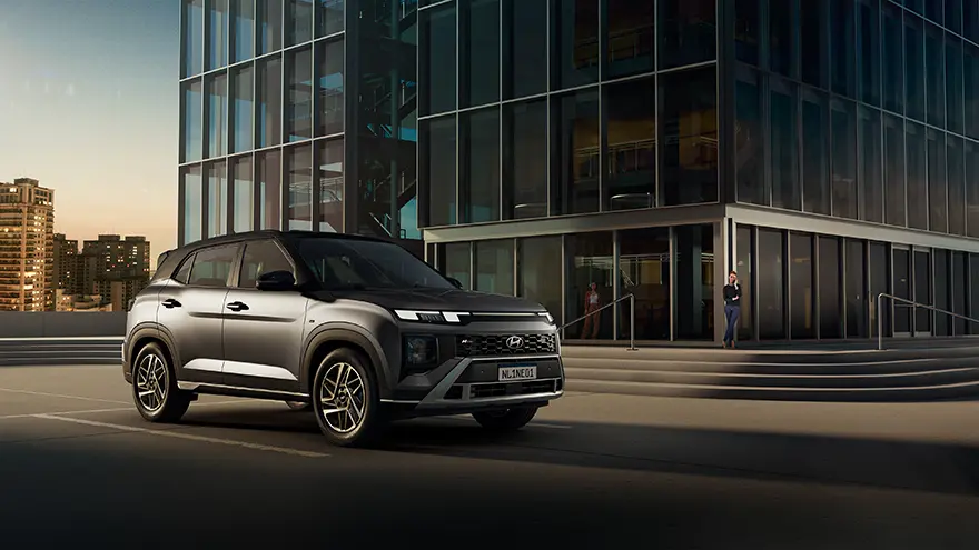 Modelo CRETA N Line na cor cinza estacionado na rua durante o dia com prédio ao fundo.